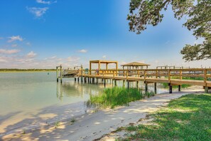 A wooden pier extending over calm water, with a covered seating area and a grassy bank. - 'Reel Blessed' Topsail Beach Home w/ Private Dock! (Topsail Beach)