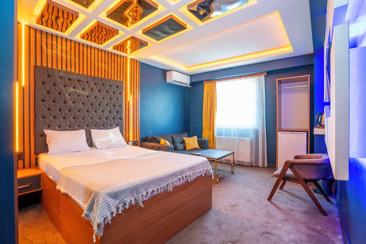 Een moderne hotelkamer met een groot bed, een sofa, een klein tafeltje en een stoel.