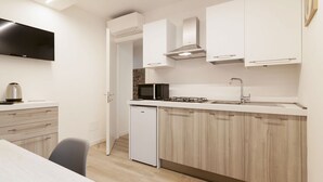 A modern kitchen with white cabinetry, a built-in microwave, and a gas stove.