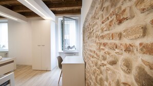 A modern interior with exposed brick walls, a wooden ceiling, and a white desk area.