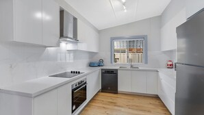 Een moderne keuken met witte kastjes, een inbouwoven, een vaatwasser en een roestvrijstalen koelkast.