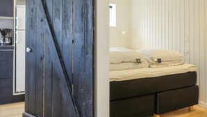 A room with a bed, a dark wooden door, and a white wall with vertical blinds. - Nice home in Nexø with WiFi (Nexø)