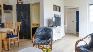 A cozy living room with a dining area, a television, and a large furry chair. - Nice home in Nexø with WiFi (Nexø)