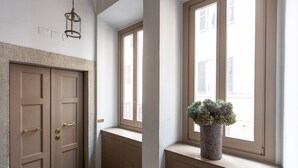 Ein Flur mit einer Tür, einer Bank und einem Fenster mit Blumentopf.