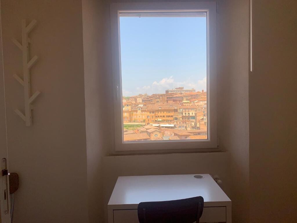 A room with a desk and a window overlooking a cityscape.