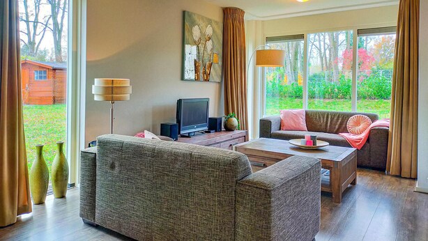 A living room with a sofa, armchair, and a television on a wooden table.