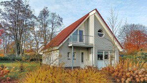 A two-story house with a red-tiled roof, surrounded by autumn foliage.