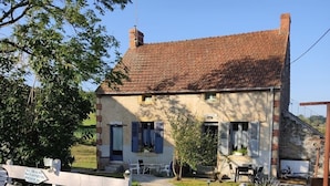 Ein rustikales Steinhaus mit einem Schotterweg, der zu einem weißen Tor führt.