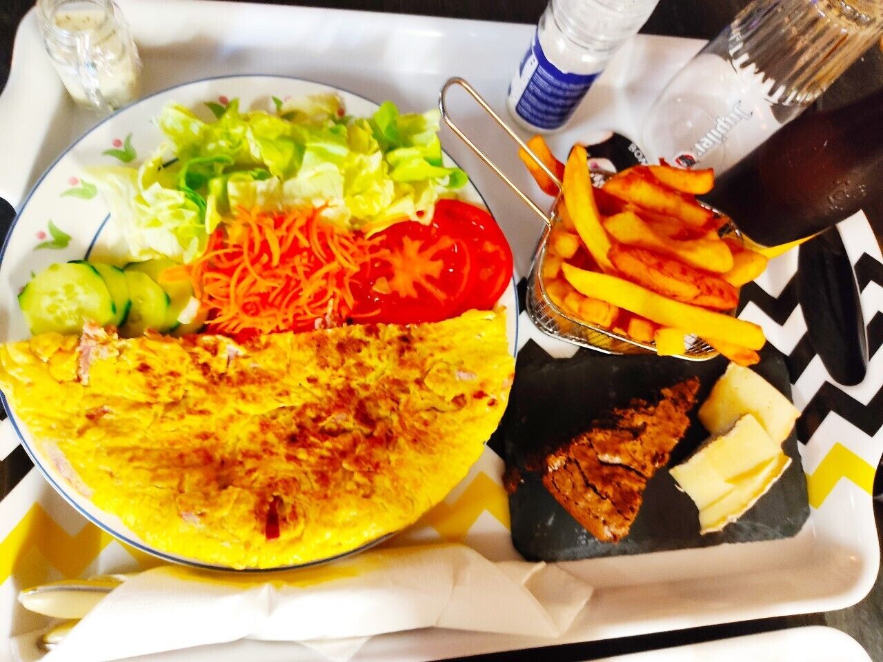 A tray with a wrap, salad, fries, and a drink.