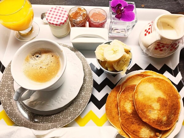 A breakfast tray with a cup of coffee, pancakes, a glass of orange juice, and various condiments. - Chez Christy (Saint-Bonnet-de-Four)