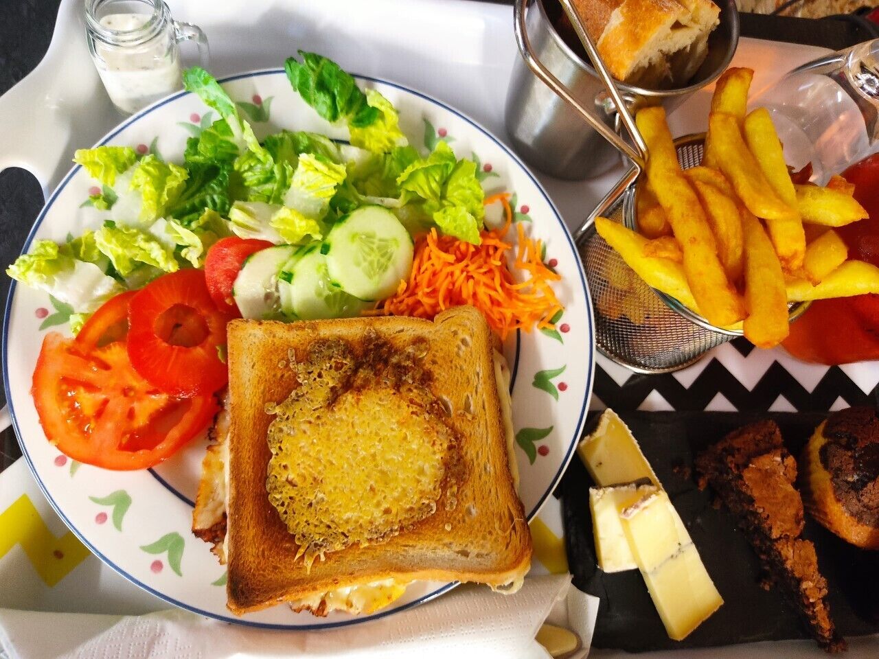 A plate with a sandwich, salad, fries, and cookies.