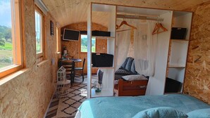 Ein gemütliches Schlafzimmer mit Bett, Fernseher, Schreibtisch und Stuhl.