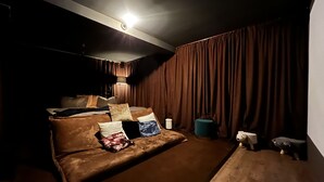 Una stanza poco illuminata con un letto grande, un tavolino e una tenda.