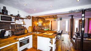 Una cucina compatta con piano di lavoro in legno, forno integrato, microonde e lavello.