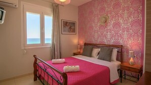 A bedroom with a bed, bedside tables, a window, and a patterned wall. - Tranquil Villa overlooking the Cretan sea (Arkadi)