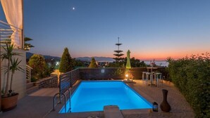 A rooftop swimming pool with a view of the sunset and mountains in the background. - Tranquil Villa overlooking the Cretan sea (Arkadi)