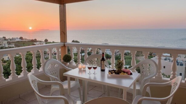 A balcony with a table set for two, overlooking a sunset over the sea. - Tranquil Villa overlooking the Cretan sea (Arkadi)