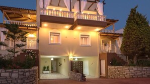 A two-story building with a balcony, a stone wall, and a gate. - Tranquil Villa overlooking the Cretan sea (Arkadi)
