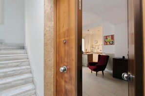 A staircase leading to a room with a red chair and a kitchen area in the background.