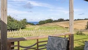 A wooden pergola with a view of a grassy field and a body of water in the distance. - Awesome apartment in Hasle (Hasle)