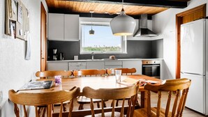 A modern kitchen with white cabinets, a wooden dining table, and a large window. - Awesome apartment in Hasle (Hasle)