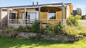 A covered outdoor seating area with a stone wall and wooden benches. - Awesome apartment in Hasle (Hasle)