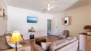 A living room with a sofa, a lamp, a TV, a fireplace, and a mirror. - Veronica Court 1, 4 Weatherly Cl - Aircon (Nelson Bay)