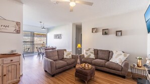 A spacious living room with two sofas, a coffee table, and a dining area with a balcony view. - Veronica Court 1, 4 Weatherly Cl - Aircon (Nelson Bay)