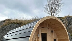 A wooden sauna with a curved exterior and a wooden deck leading to the entrance. - The QV Stage, Lux Couples Retreat W/ Outdoor Sauna (St. John's)