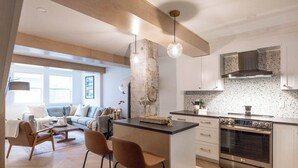 A modern kitchen with a central island, stainless steel appliances, and a speckled backsplash. - The QV Stage, Lux Couples Retreat W/ Outdoor Sauna (St. John's)