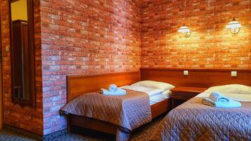 Habitació d'hotel amb dos llits, una paret de maó i dues làmpades penjades a la paret.