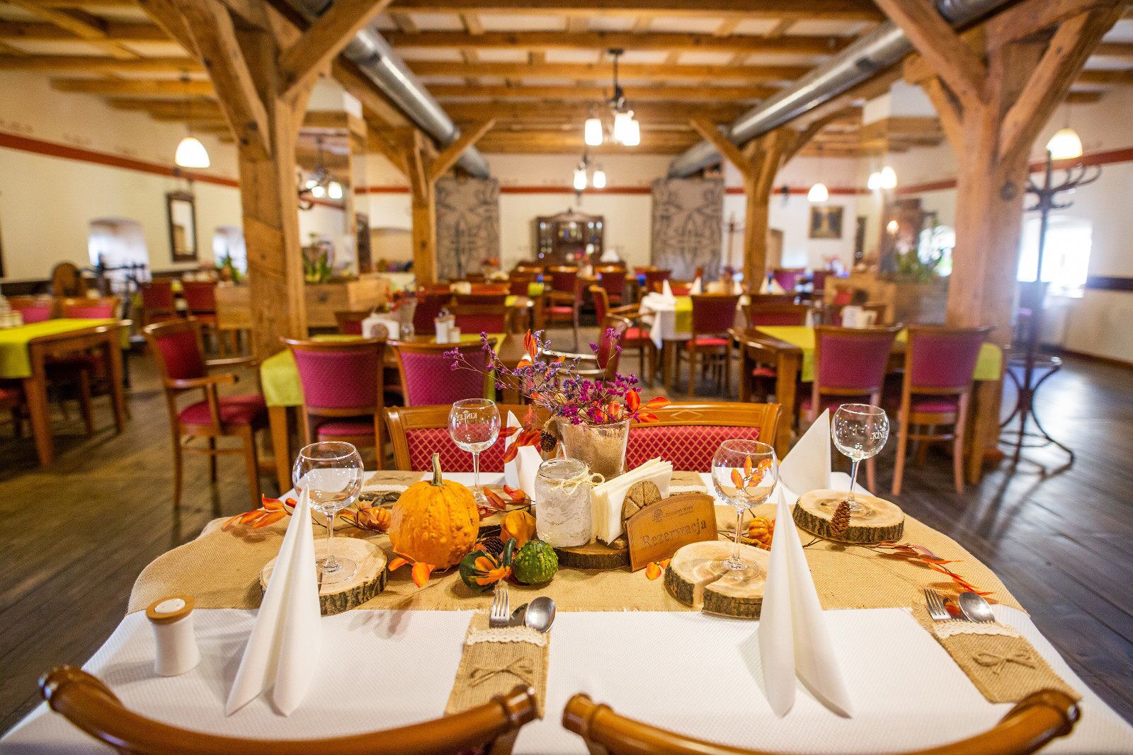 Un restaurante con vigas de madera, mesas dispuestas con manteles blancos y una variedad de platos y bebidas.