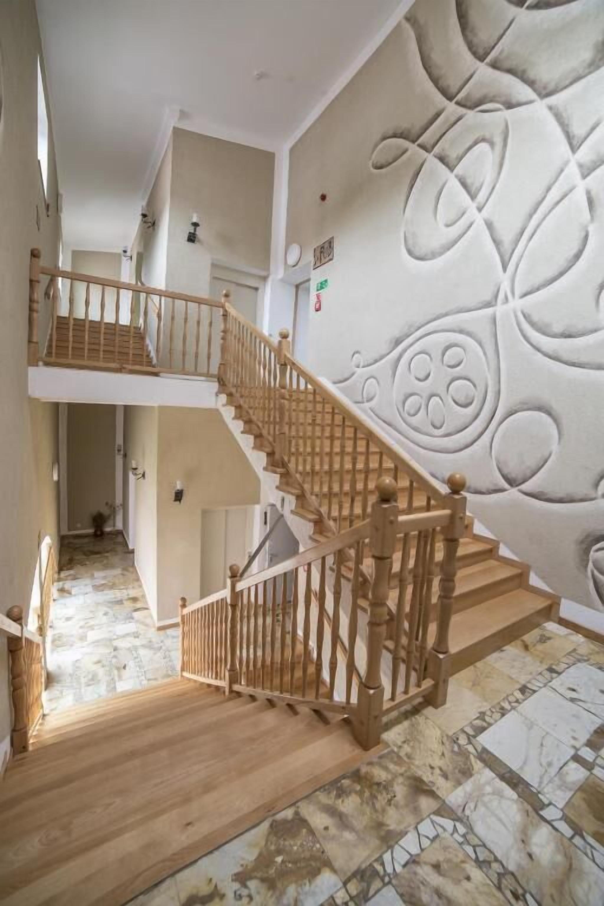 Una escalera con barandillas de madera y un revestimiento mural estampado.