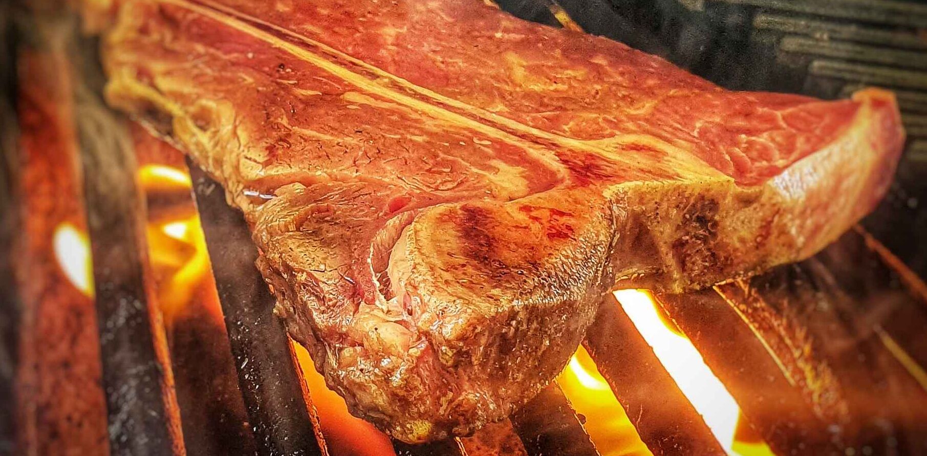 Un gros morceau de viande est en train de cuire sur une flamme nue.
