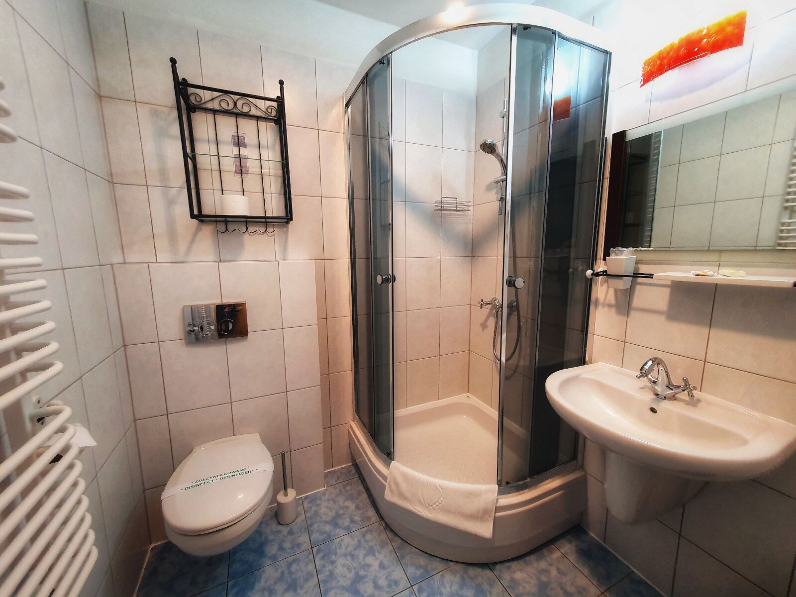 A bathroom with a glass-enclosed shower, a toilet, a sink, and a towel rack.