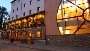 Un edificio con un gran ventanal de arco y varios balcones con mesas al aire libre.