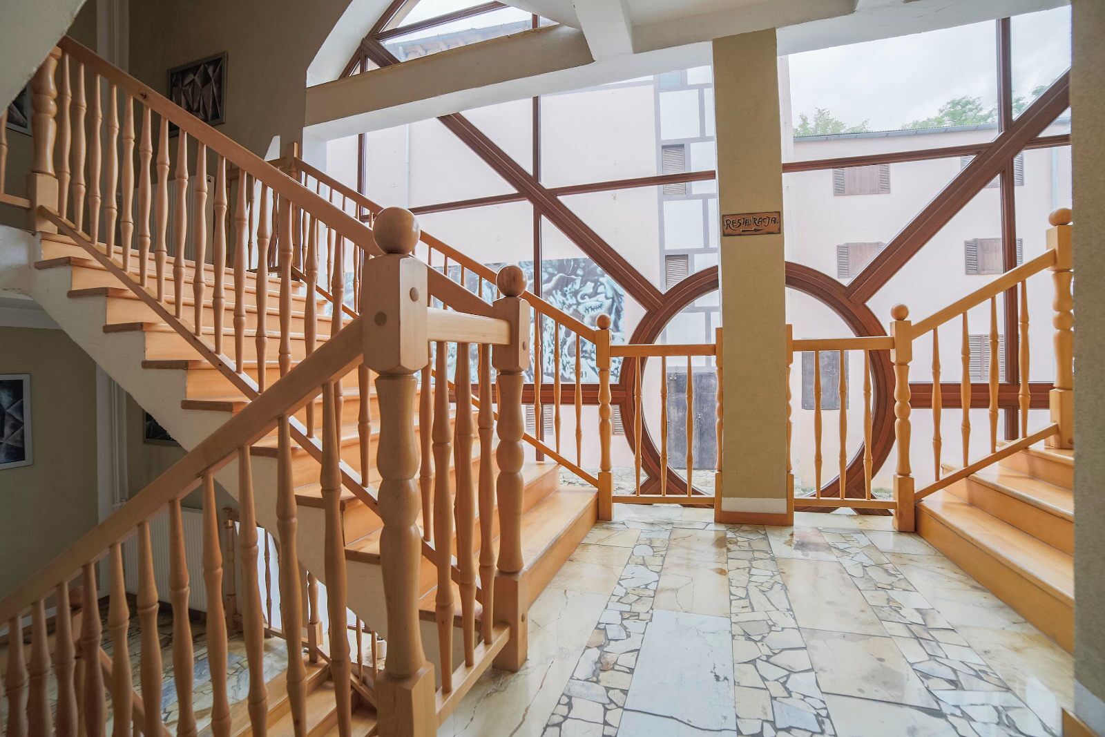 Una escalera de madera con suelo de mármol que lleva a un segundo nivel.