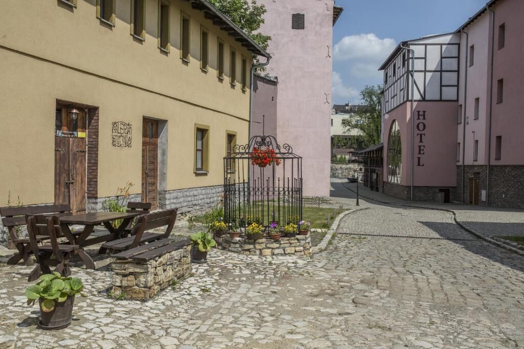 A cobblestone street with a wooden bench and a metal flower pot.