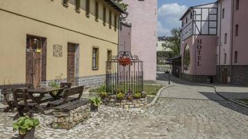 A cobblestone street with a wooden bench and a metal flower pot.