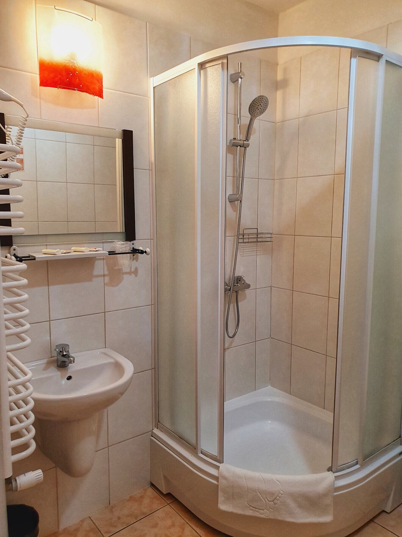 Ein Badezimmer mit einer Duschkabine, einem Waschbecken und einem Handtuchhalter.