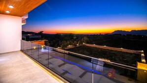 Un balcon moderne avec une balustrade en verre offrant une vue imprenable sur le coucher du soleil.