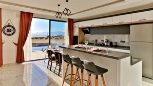 Une cuisine moderne dotée d’un îlot central, de tabourets de bar et offrant une vue sur le paysage.