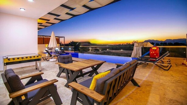 Une terrasse sur le toit avec une piscine, des chaises longues et une table de baby-foot.