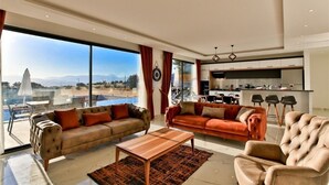 Un salon spacieux avec deux canapés, une table basse et une vue sur une piscine et des montagnes.
