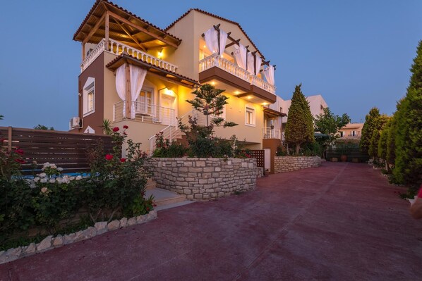 A two-story house with a stone wall and a paved driveway.