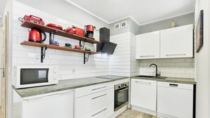 Una cocina moderna con armarios blancos, microondas integrado, estufa y lavavajillas.