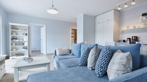 Una sala de estar moderna con un sofá azul, una mesa de centro blanca y una estantería.