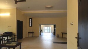 Un hall d’hôtel spacieux, doté d’un plafond haut, d’un ventilateur de plafond et offrant une vue sur l’extérieur à travers une porte vitrée.