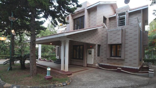 Un bâtiment à deux étages doté d’une entrée couverte, d’une antenne parabolique et d’un petit jardin avec un arbre et un lampadaire.