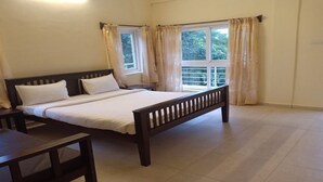 Une chambre à coucher avec un lit, un bureau et deux fenêtres avec des rideaux.
